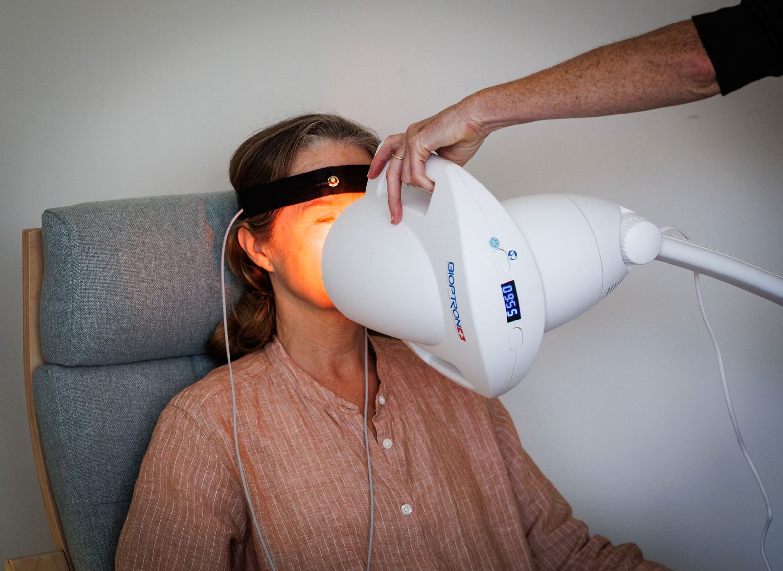 A client resting with her eyes closed as Caroline positions the warm Bioptron light