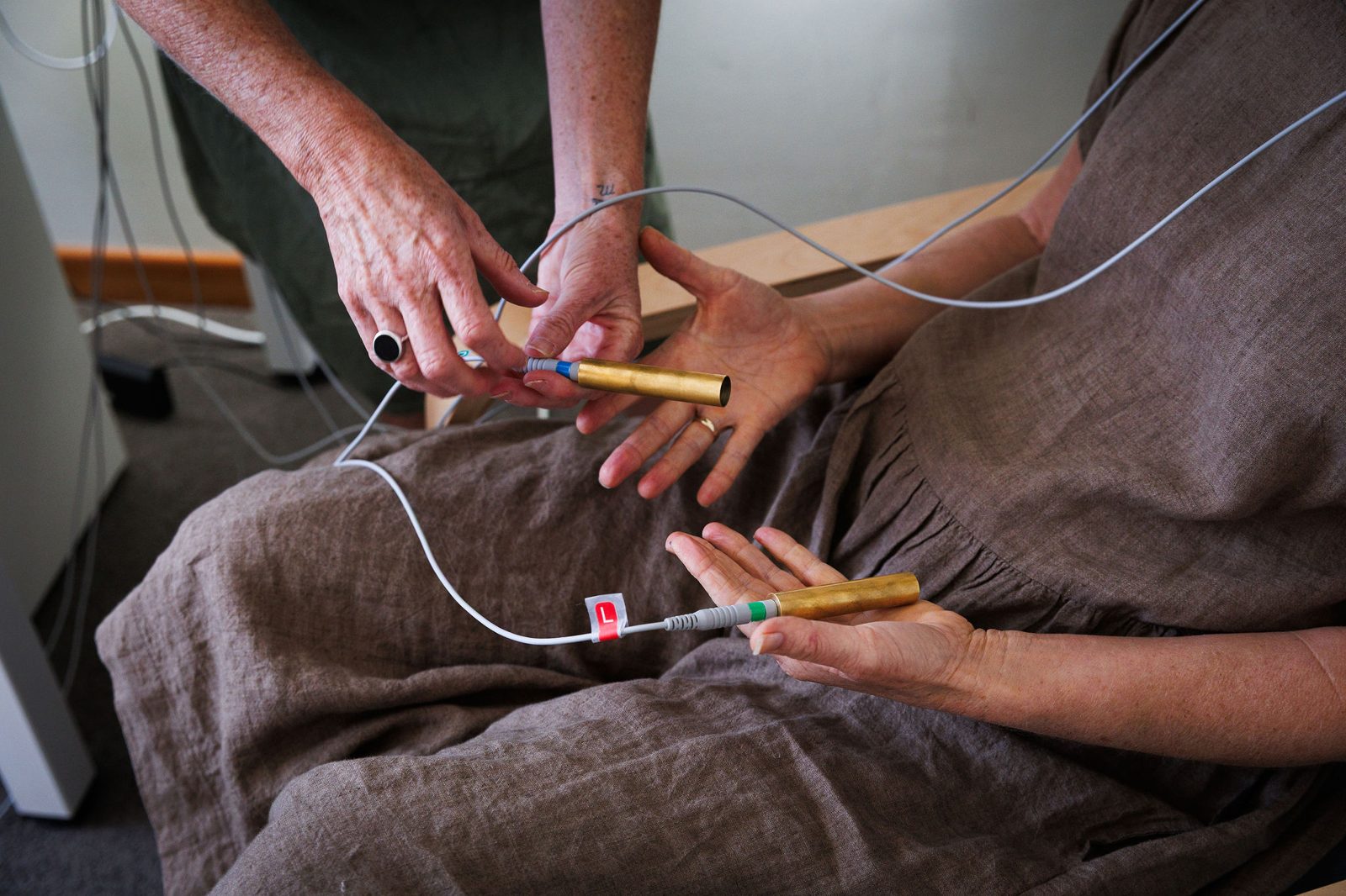 Caroline placing a brass hand electrode into a client's open palm